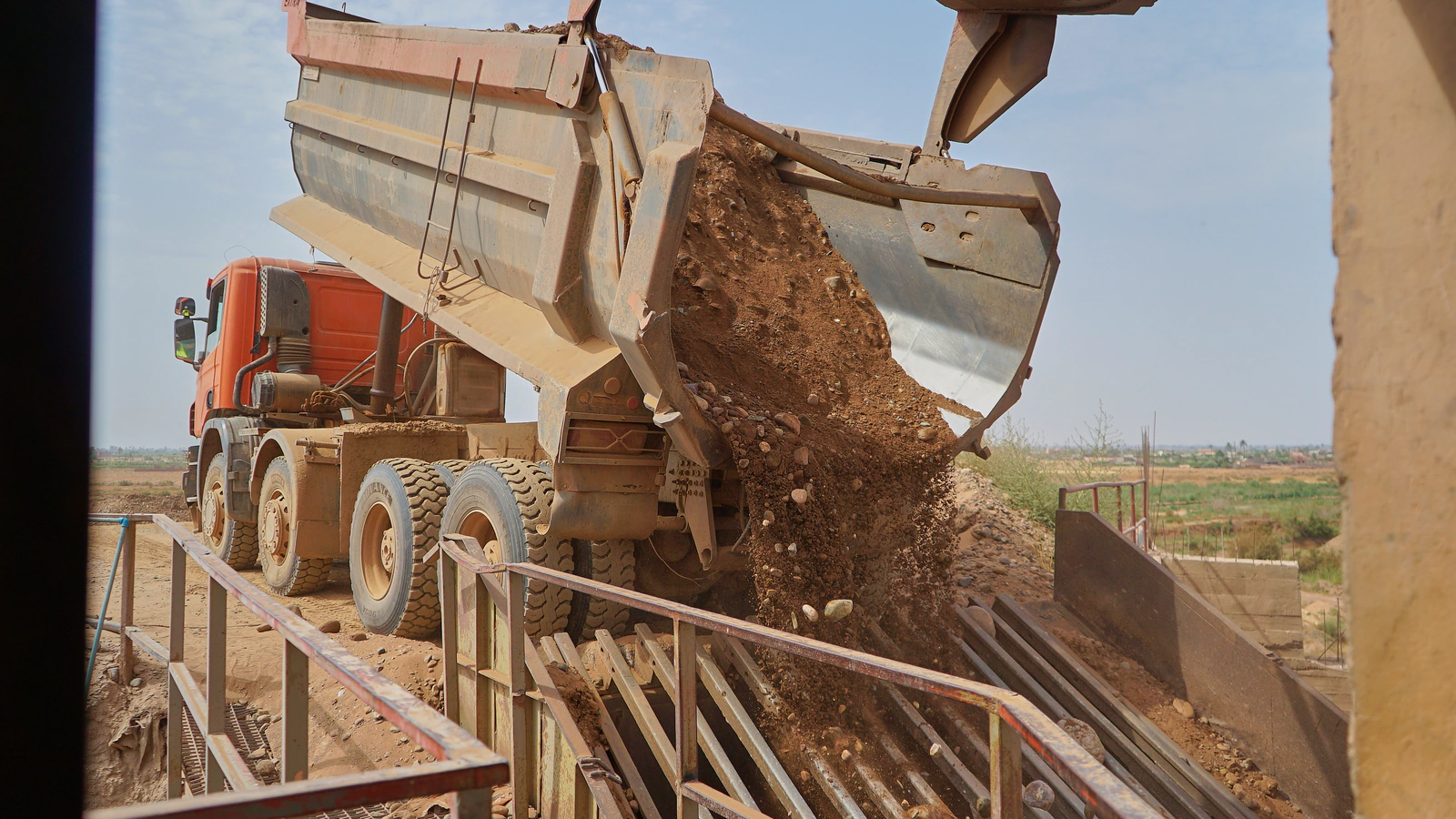 Camion benne déchargeant des matériaux dans la trémie d’alimentation d’une station Agré Béton